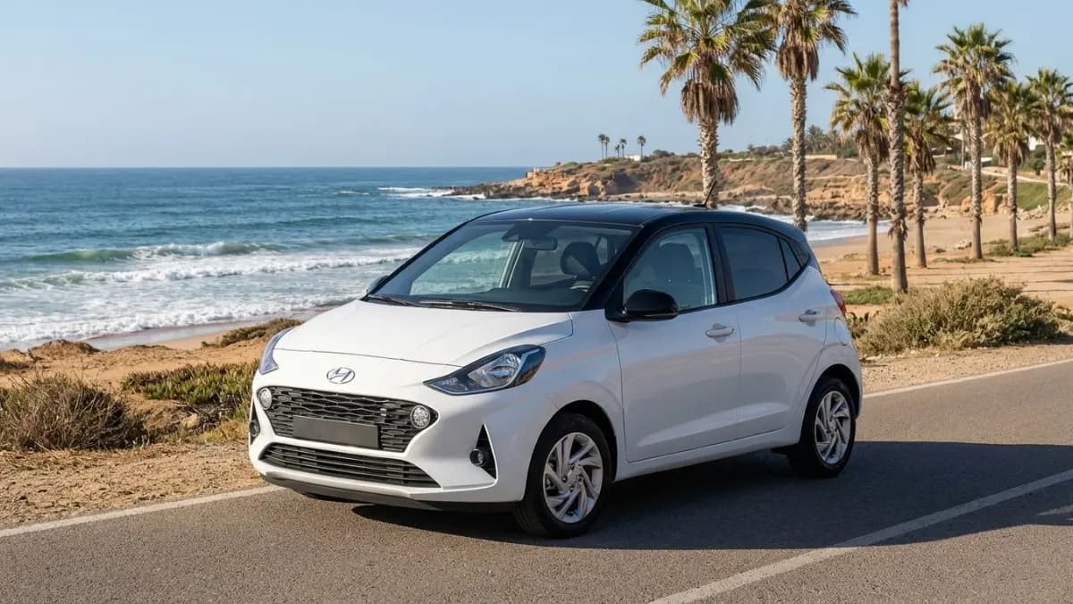 Une Hyundai i10 garée sur une route côtière au Maroc, avec vue sur l’océan Atlantique et palmiers, Hyundai i10.