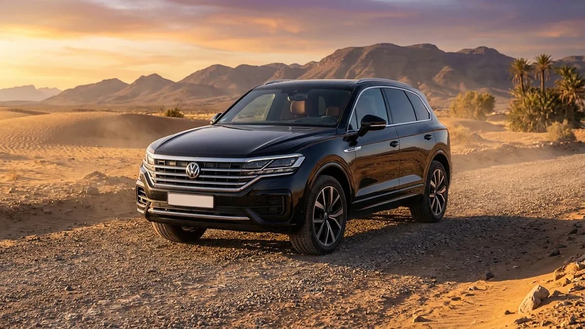 Vue de profil d’un SUV Volkswagen Touareg 2025 noir sur une route panoramique désertique marocain au lever du soleil, avec dunes à l’horizon.